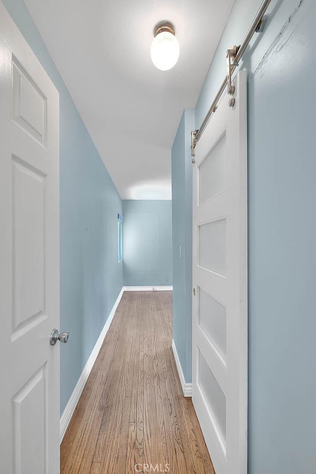 hall with light hardwood / wood-style floors and a barn door