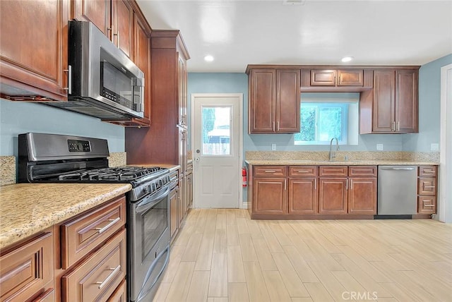 kitchen featuring stainless steel appliances, light stone countertops, sink, and light hardwood / wood-style floors