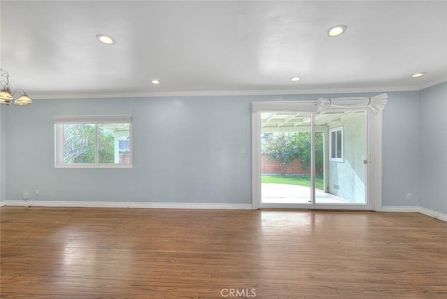 unfurnished room with hardwood / wood-style floors, crown molding, and a chandelier