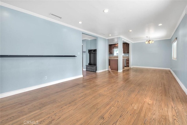 unfurnished living room with crown molding, hardwood / wood-style flooring, and an inviting chandelier