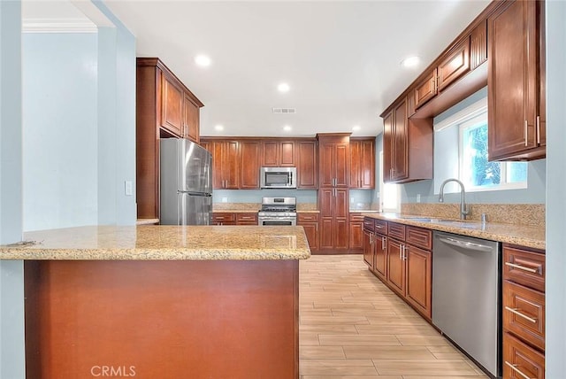 kitchen featuring light stone countertops, appliances with stainless steel finishes, sink, and kitchen peninsula