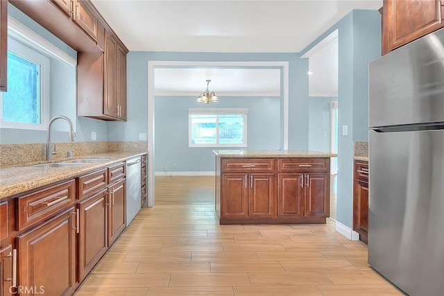 kitchen with stainless steel appliances, light stone countertops, sink, and light hardwood / wood-style flooring