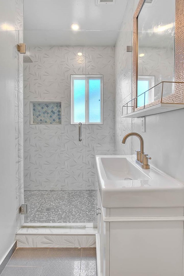 bathroom featuring a shower with door, vanity, and tile patterned floors