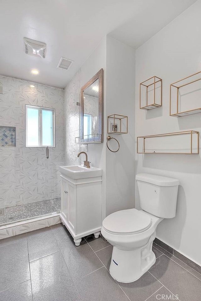 bathroom with vanity, tile patterned floors, toilet, and tiled shower