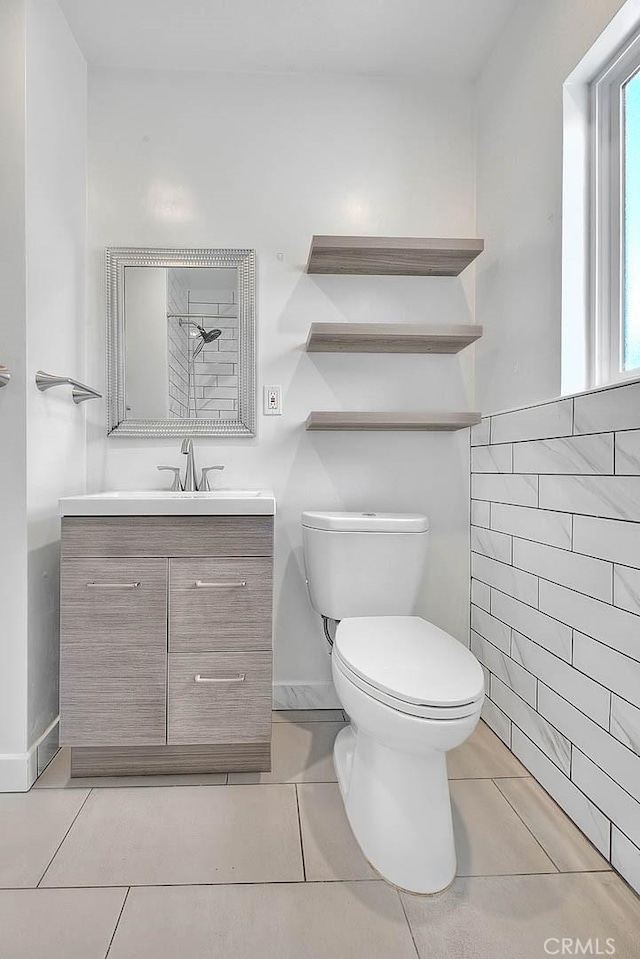 bathroom featuring vanity, tile patterned floors, tile walls, and toilet