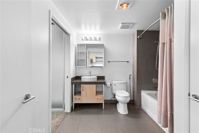 full bathroom with shower / bath combination with curtain, tile patterned flooring, vanity, toilet, and a textured ceiling