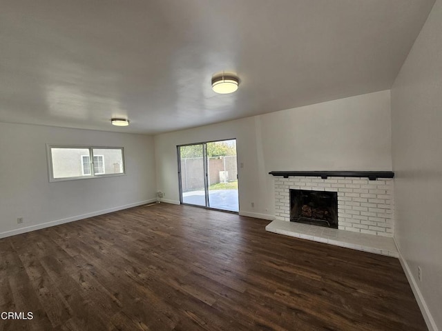 unfurnished living room featuring dark wood-type flooring and a fireplace