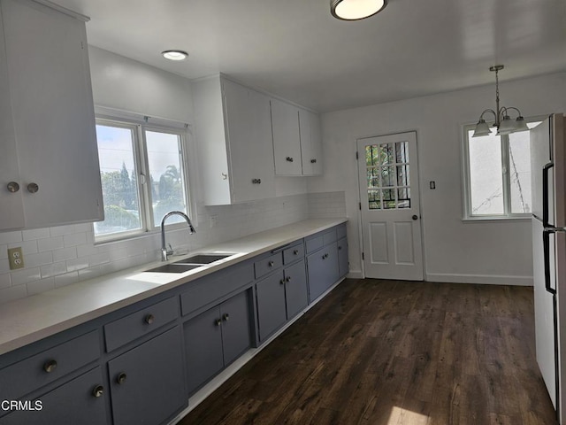 kitchen with sink, white cabinetry, dark hardwood / wood-style flooring, white fridge, and pendant lighting