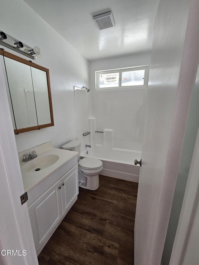 full bathroom with hardwood / wood-style flooring, vanity, shower / washtub combination, and toilet