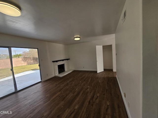 unfurnished living room with dark wood-type flooring and a fireplace