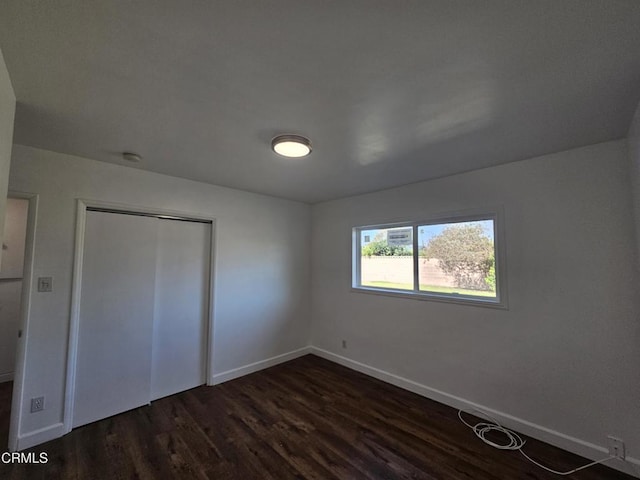 unfurnished bedroom featuring dark wood-type flooring and a closet