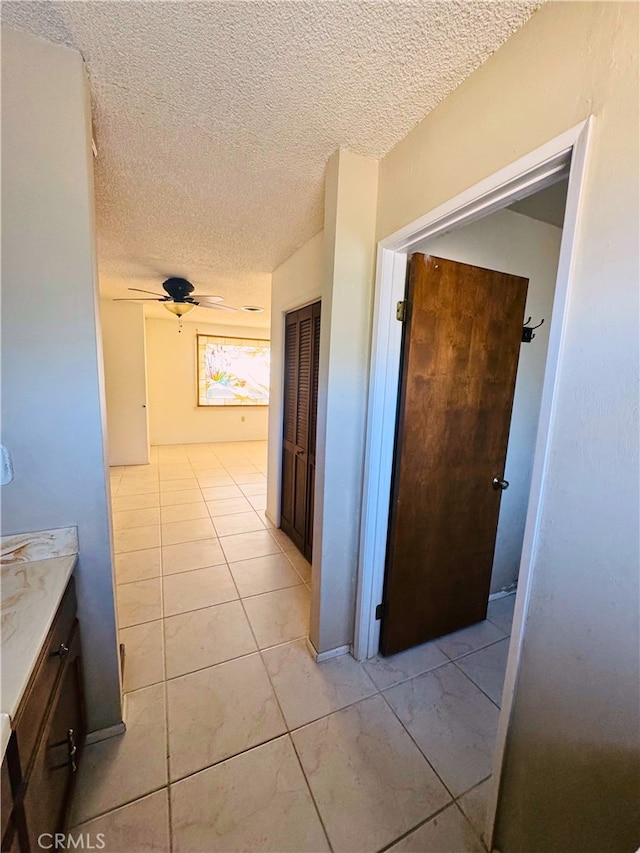 corridor featuring a textured ceiling and light tile patterned floors