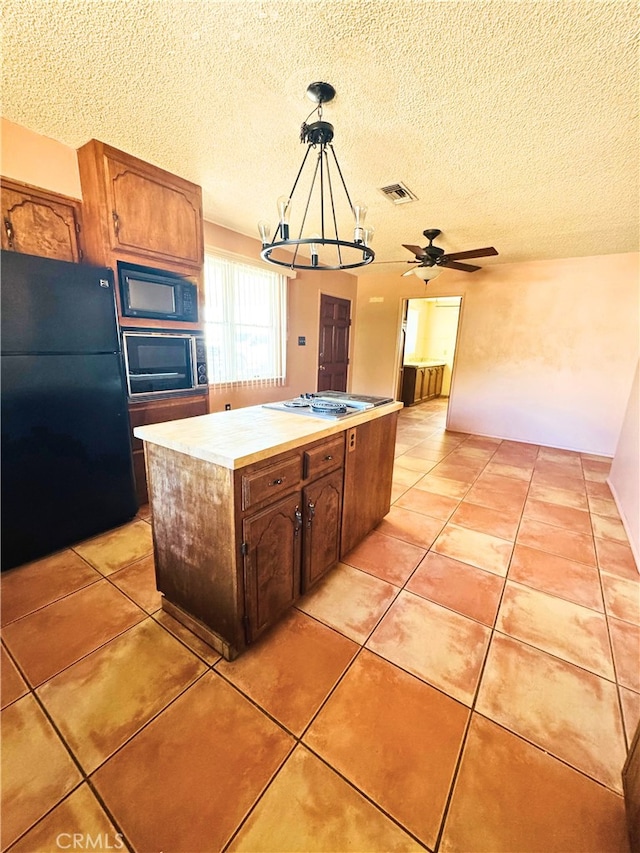 kitchen featuring pendant lighting, light tile patterned floors, black appliances, and a kitchen island