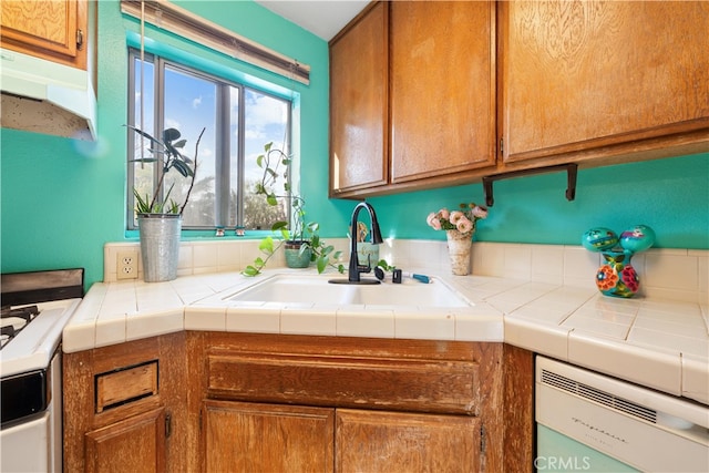 kitchen with sink, tile countertops, and dishwashing machine