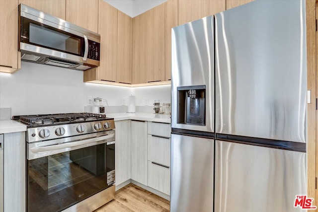 kitchen with light brown cabinetry, light hardwood / wood-style flooring, and stainless steel appliances