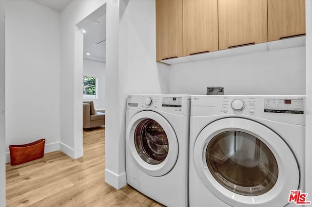 laundry area with cabinets, separate washer and dryer, and light hardwood / wood-style flooring