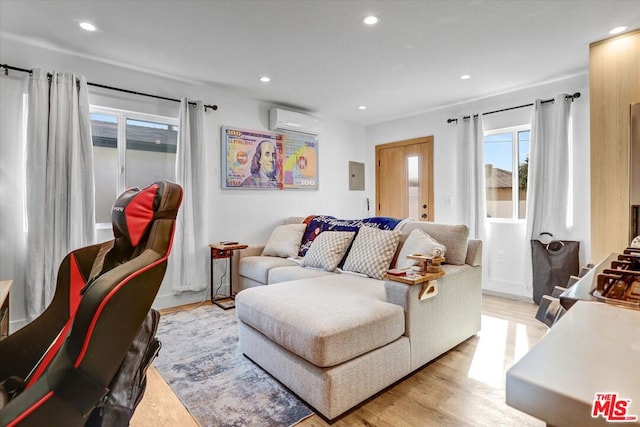 living room with an AC wall unit, electric panel, and light wood-type flooring