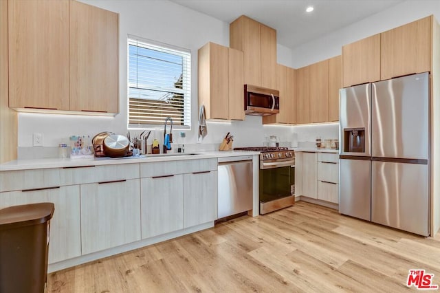 kitchen featuring stainless steel appliances, sink, light brown cabinets, and light hardwood / wood-style flooring