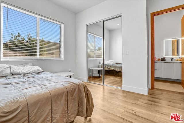 bedroom featuring sink, light hardwood / wood-style floors, and a closet