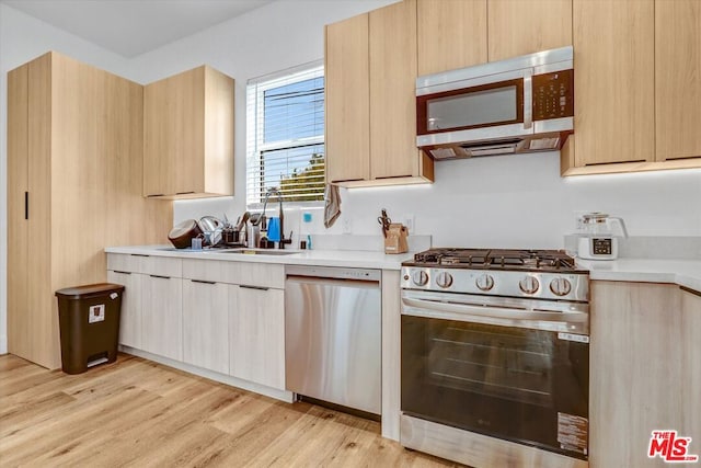 kitchen featuring sink, light hardwood / wood-style flooring, light brown cabinets, and appliances with stainless steel finishes