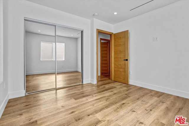 unfurnished bedroom featuring light wood-type flooring and a closet