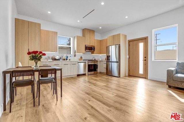 kitchen with stainless steel appliances, light brown cabinetry, and light wood-type flooring