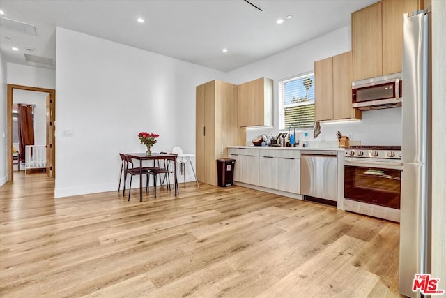 kitchen featuring stainless steel appliances, light brown cabinetry, and light wood-type flooring