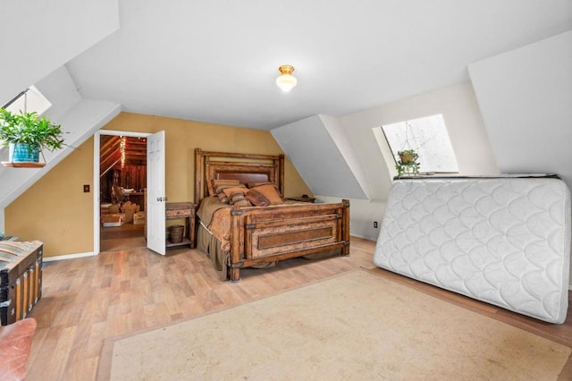 bedroom with vaulted ceiling with skylight and light wood-type flooring