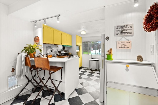 kitchen with stainless steel stove, rail lighting, a breakfast bar, built in microwave, and kitchen peninsula