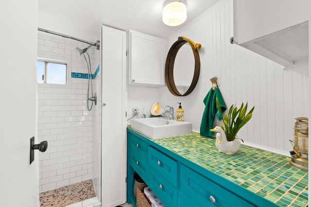 bathroom featuring tiled shower and vanity