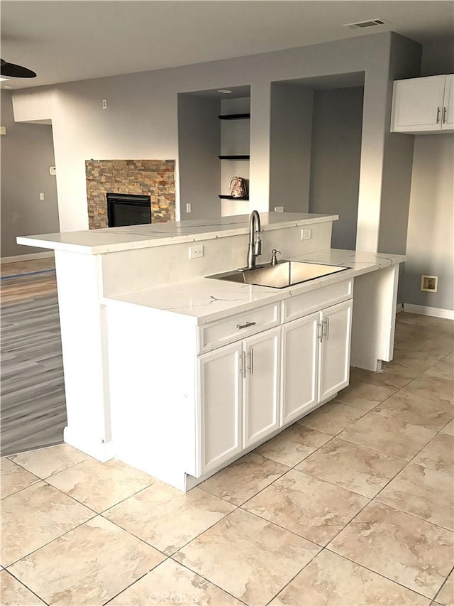 kitchen with white cabinetry, sink, an island with sink, and ceiling fan