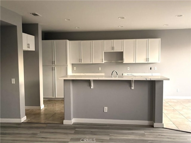 kitchen featuring a breakfast bar, sink, a center island with sink, and white cabinets