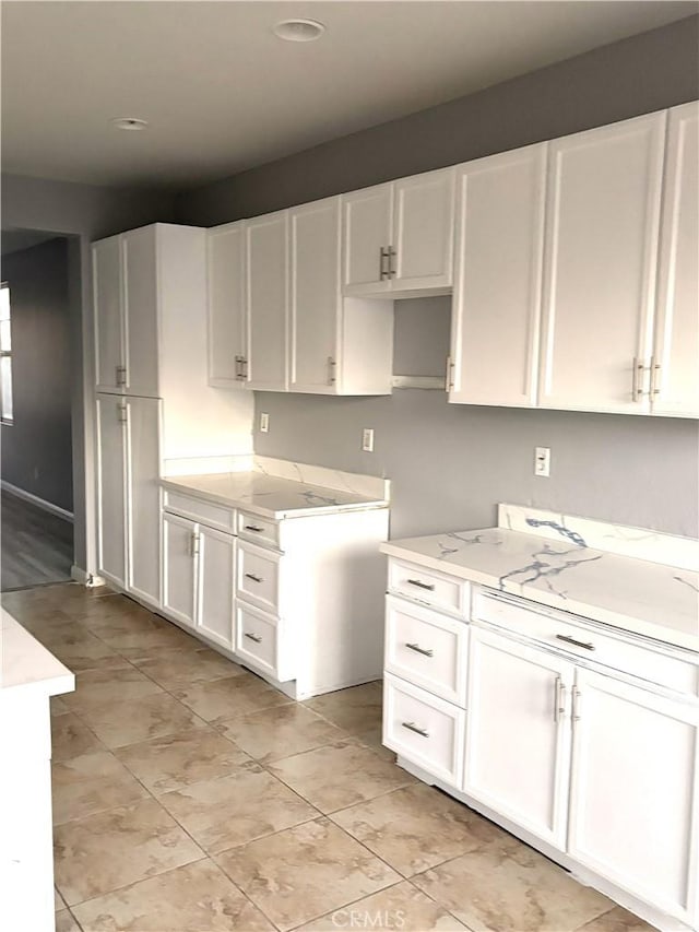 kitchen featuring light stone counters and white cabinets