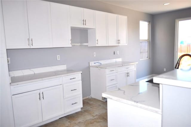 kitchen featuring white cabinetry and light stone counters