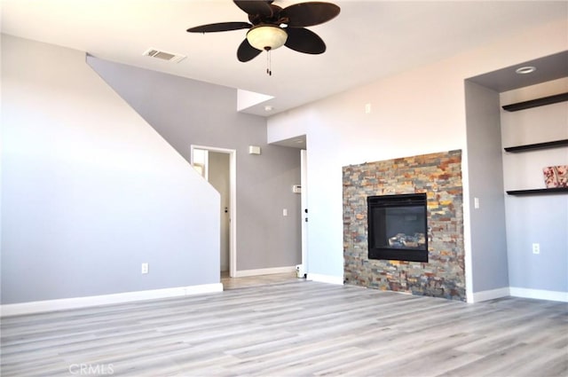 unfurnished living room with ceiling fan, a fireplace, and light hardwood / wood-style floors