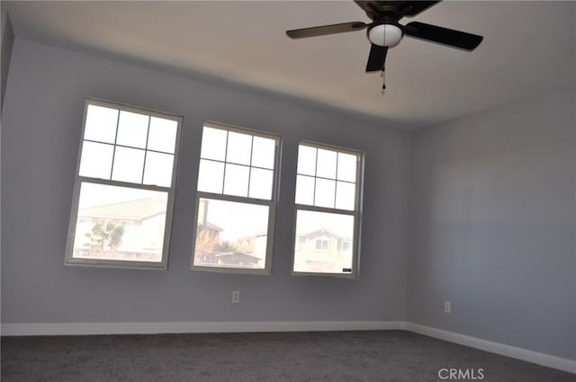 spare room with ceiling fan and dark colored carpet