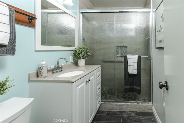 bathroom featuring vanity, a shower with shower door, and toilet