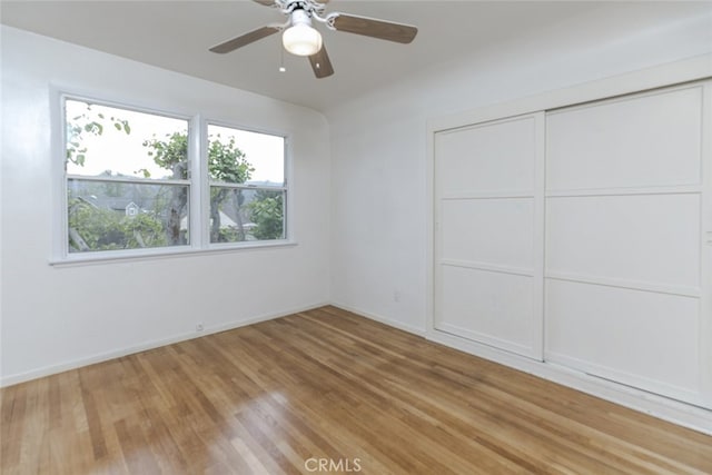 unfurnished bedroom featuring wood-type flooring, ceiling fan, and a closet