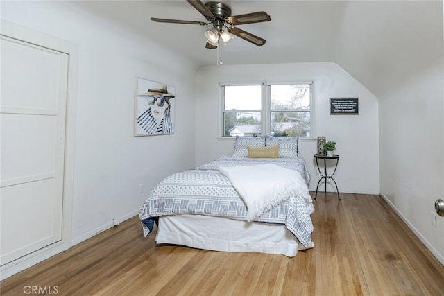 bedroom with hardwood / wood-style flooring, ceiling fan, and vaulted ceiling