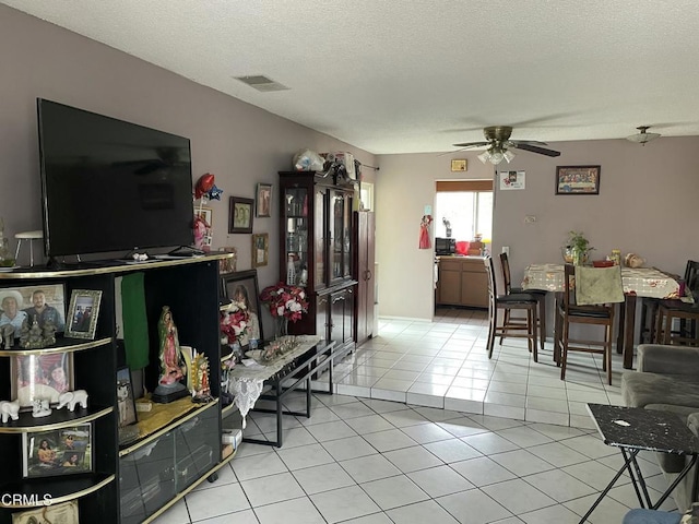 living room with ceiling fan, a textured ceiling, and light tile patterned flooring