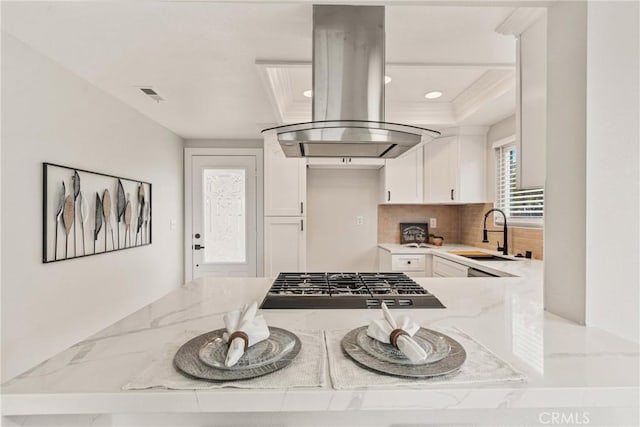 kitchen featuring white cabinetry, island range hood, sink, and light stone counters