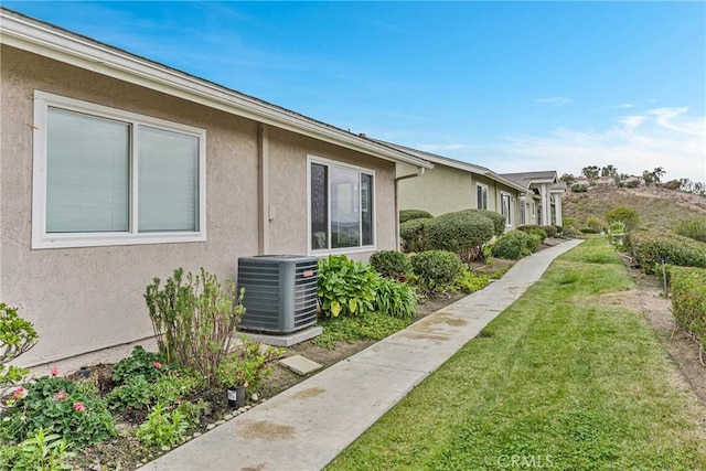 view of side of home with a yard and central AC