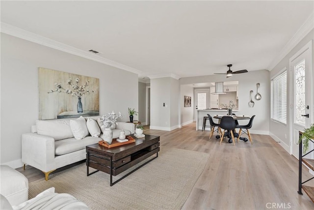 living room featuring crown molding, ceiling fan, and light wood-type flooring