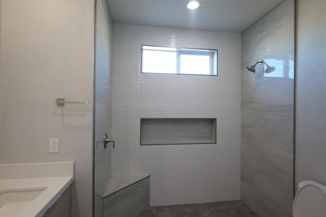 bathroom featuring vanity, toilet, and a tile shower