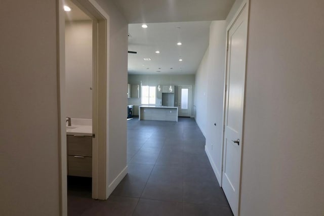 hall featuring sink and dark tile patterned floors