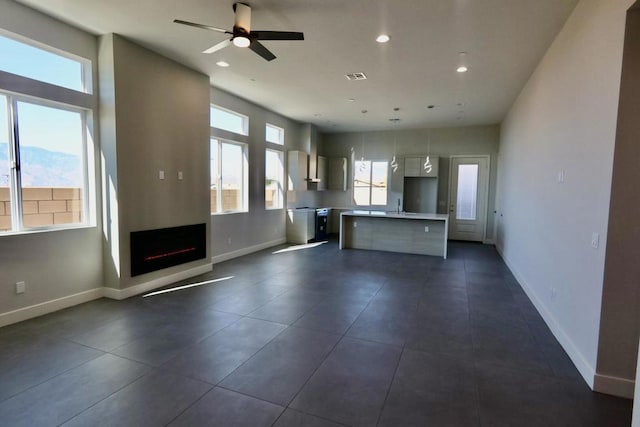 kitchen with ceiling fan, decorative light fixtures, a center island, and sink