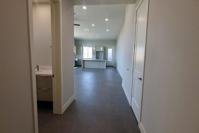 corridor with sink and dark tile patterned floors