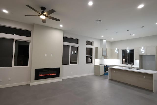 kitchen featuring wall chimney range hood, stainless steel electric stove, a center island, and white cabinets