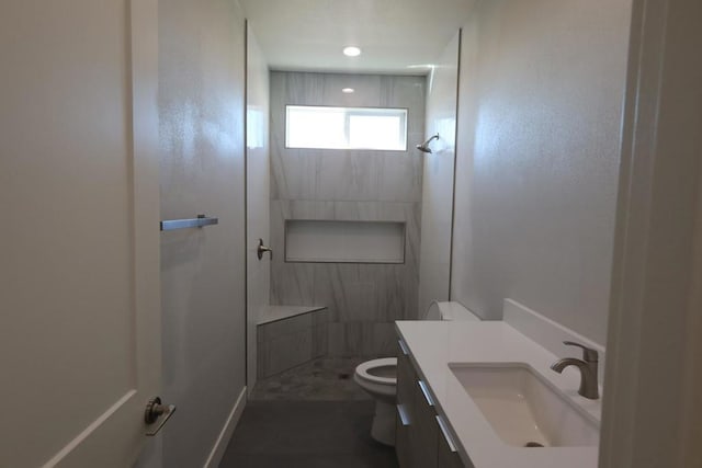 bathroom with vanity, toilet, and a tile shower