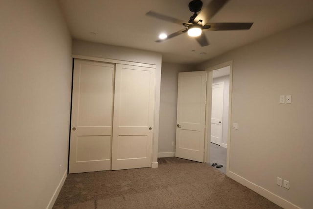 unfurnished bedroom featuring ceiling fan, dark carpet, and a closet